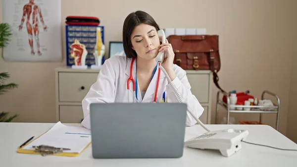Young Beautiful Hispanic Woman Doctor Using Laptop Talking Telephone Clinic — Stock Photo, Image