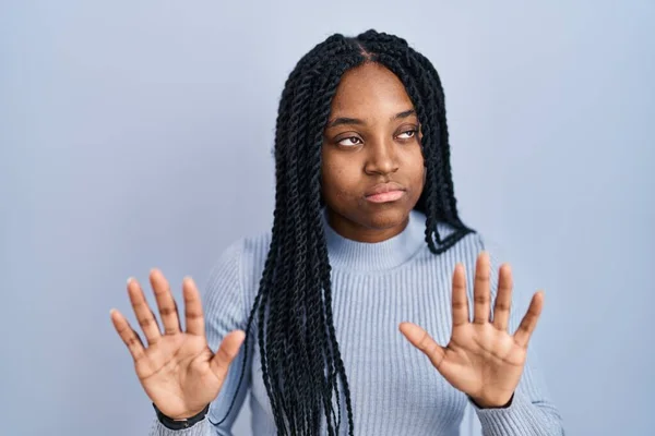 青い背景の上に立っているアフリカ系アメリカ人女性は 恐怖と嫌な表情で拒否と否定を示す手のひらを離れて移動します 止めて禁止する — ストック写真