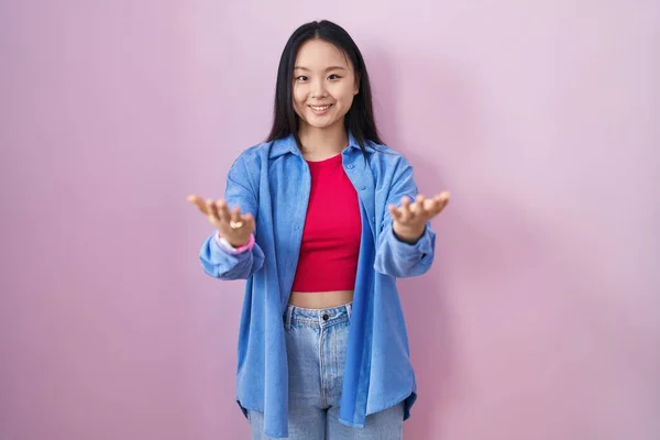 Young Asian Woman Standing Pink Background Smiling Cheerful Offering Hands — Stockfoto