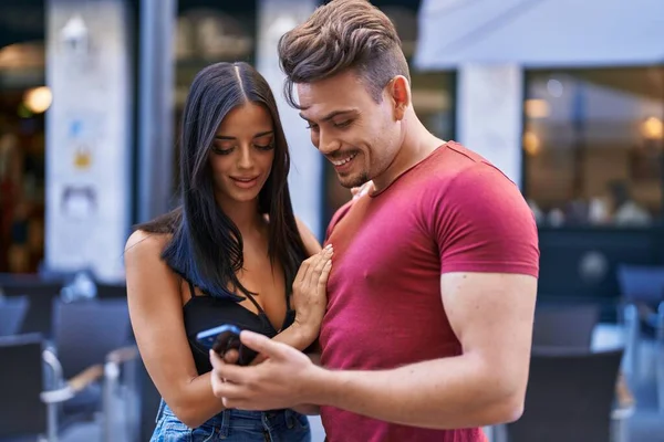男性と女性のカップル笑顔自信を持って使用してスマートフォンでコーヒーショップテラス — ストック写真