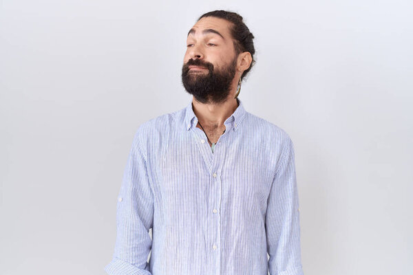 Hispanic man with beard wearing casual shirt smiling looking to the side and staring away thinking. 