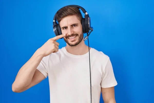 Hiszpan Brodą Słuchający Muzyki Słuchawkami Wskazującymi Palcem Twarz Nos Uśmiechający — Zdjęcie stockowe