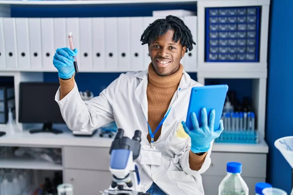 アフリカ系アメリカ人の男性科学者は 実験室でタッチパッド保持試験管を使用して — ストック写真