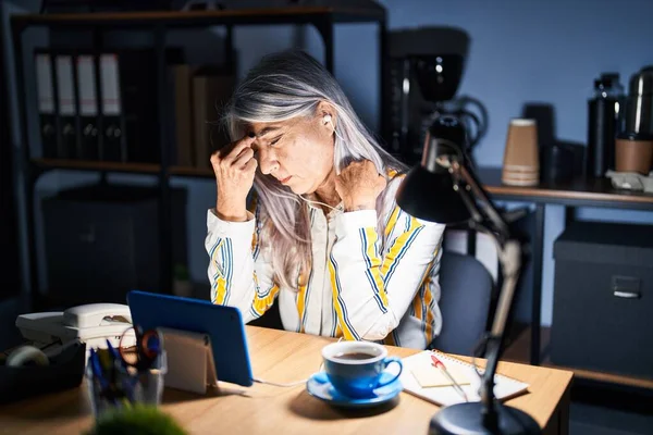 夜のオフィスで働く白髪の中年女性は鼻をこすり 目は疲労感と頭痛を感じます ストレスとフラストレーションの概念 — ストック写真
