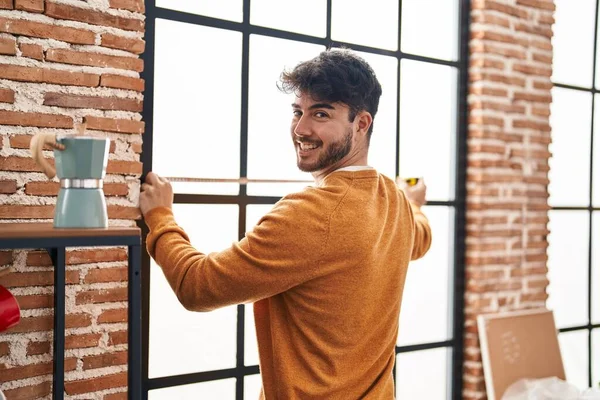Young Hispanic Man Smiling Confident Measuring Window New Home — Stock fotografie