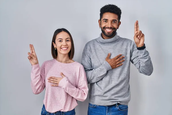 Young Hispanic Couple Standing Together Smiling Swearing Hand Chest Fingers — Stock Photo, Image