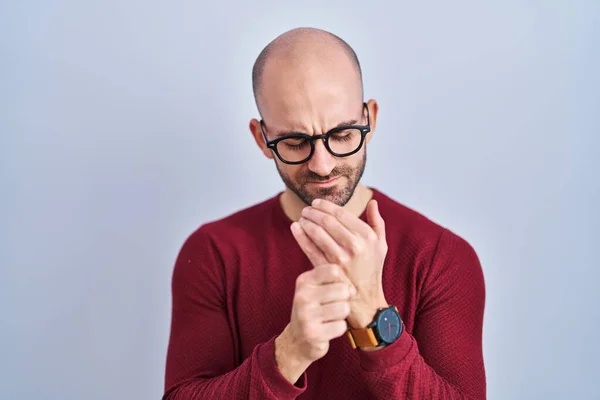 stock image Young bald man with beard standing over white background wearing glasses suffering pain on hands and fingers, arthritis inflammation 