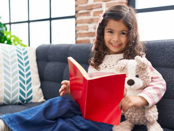 Adorable Hispanic Girl Reading Book Sitting Sofa Home — Stockfoto
