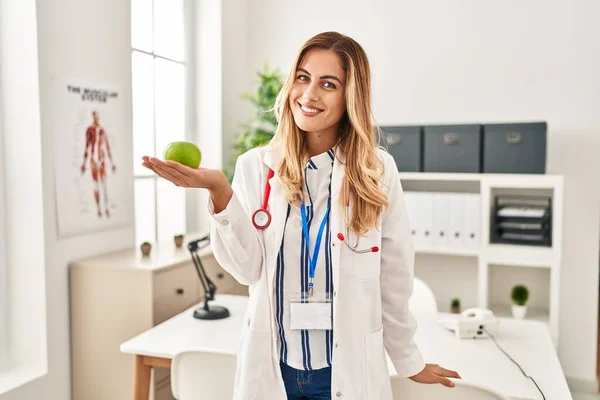 Young Blonde Woman Wearing Doctor Uniform Holding Apple Clinic — Stock Photo, Image