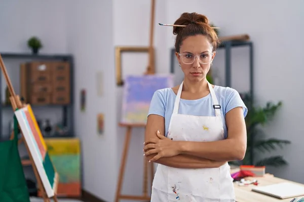 Brunette woman painting at art studio skeptic and nervous, disapproving expression on face with crossed arms. negative person.