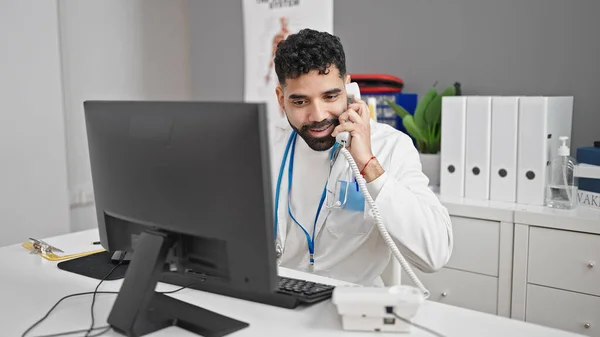 Young Hispanic Man Doctor Talking Telephone Using Computer Clinic — Stock Photo, Image