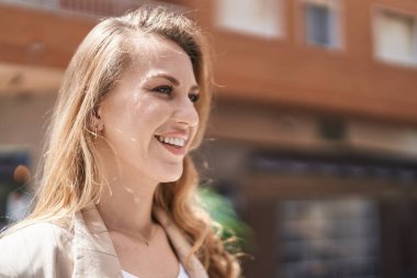 Young blonde woman smiling confident looking to the side at park