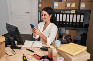 Genç, güzel, İspanyol bir kadın. İş kadını. Ofiste akıllı telefon kullanıyor.