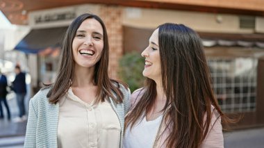 Kahve dükkanının terasında birbirine sarılan iki kadın.