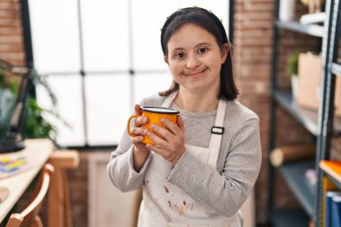 Down sendromlu genç bir kadın sanat stüdyosunda kendine güvenen ve kalem içen bir sanatçı.