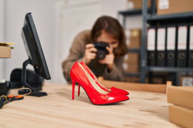 Beyaz kadın dış ticaret işçisi ofisteki yüksek topuklu ayakkabılara fotoğraf çekiyor.