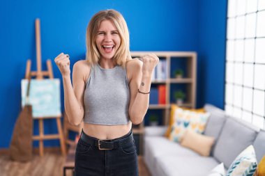 Sarışın, beyaz bir kadın oturma odasında gururla bağırıyor zaferi ve başarıyı kutluyor. 