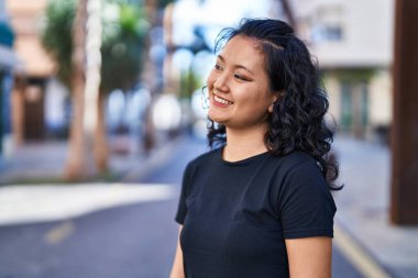 Young chinese woman smiling confident standing at street