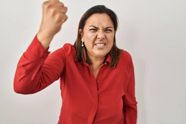 Latin kökenli olgun bir kadın, kızgın ve kızgın. Öfkeyle bağırırken yumruğunu kaldırıyor. öfke ve agresif konsept. 
