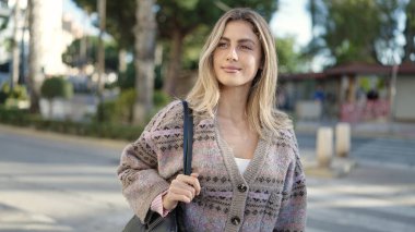 Sokakta kendine güvenen genç sarışın kadın gülümsüyor