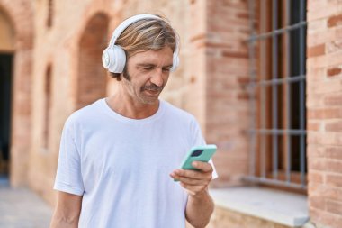 Young blond man listening to music at street