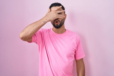 İspanyol genç adam pembe arka planda dikiliyor. Şoka giriyor. Yüzü ve gözleri kapanıyor.. 