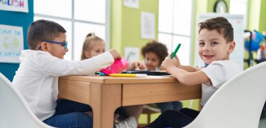 Bir grup çocuk sınıftaki not defterine resim çiziyor.