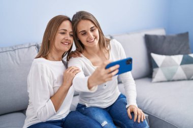 İki kadın anne ve kız evde akıllı telefondan selfie çekiyorlar.