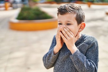 Sarışın çocuk parkta hazırlıksız duruyor.