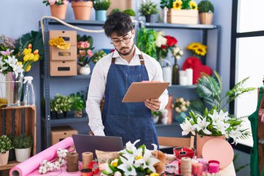Çiçekçide dizüstü bilgisayar kullanarak kitap okuyan İspanyol bir çiçekçi.