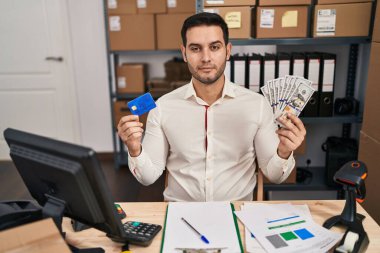Küçük işletme şirketinde sakallı genç İspanyol bir adam elinde banknotlar ve yüzünde ciddi bir ifadeyle rahatlamış bir kredi kartı tutuyordu. Basit ve doğal bir şekilde kameraya bakıyorsun.. 