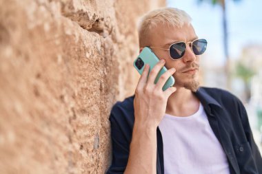 Young caucasian man talking on smartphone with serious expression at street