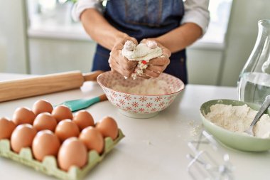Young blonde woman make pizza dough with hands at kitchen