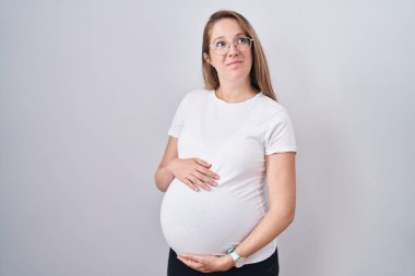 Hamile bir kadın bebek bekliyor. Hamile karnına dokunuyor. Gülümsüyor.. 