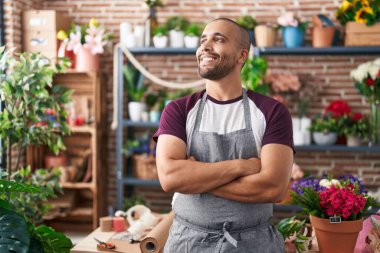 Çiçekçide kollarını kavuşturup duran kendine güvenen genç latin çiçekçi.
