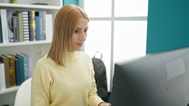 Young blonde woman student using computer studying at university classroom