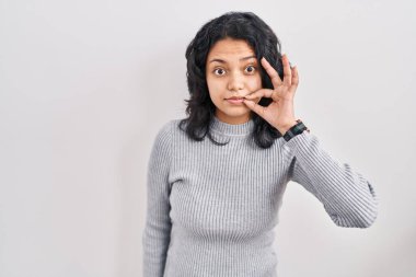 Siyah saçlı İspanyol kadın izole edilmiş arka plan ağzının başında duruyor ve dudakları parmaklarıyla fermuar gibi kapalı. gizli ve sessiz, tabu konuşması 