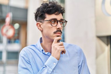 Sokakta şüpheli bir ifadeyle duran genç beyaz bir adam.