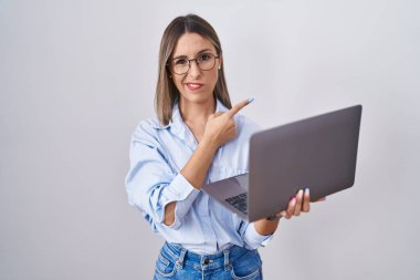 Bilgisayarla çalışan genç bir kadın endişeli ve endişeli bir ifadeyi işaret ediyor. 