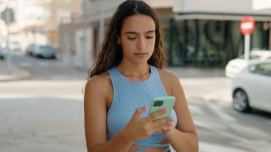 Genç ve güzel İspanyol kadın akıllı telefon kullanıyor. Sokakta ciddi bir ifadesi var.