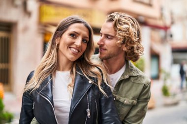 Kadın ve erkek gülümsüyor. Kendilerine güveniyorlar. Sokakta sarılıyorlar.