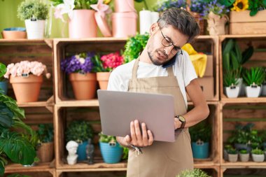 Çiçekçide dizüstü bilgisayar kullanarak konuşan İspanyol çiçekçi.