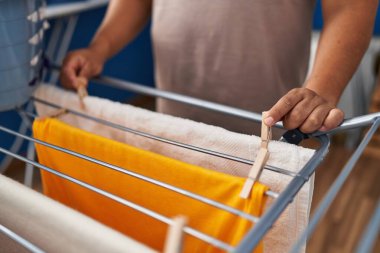 Çamaşır odasında çamaşır ipine elbise asan genç latin adam.