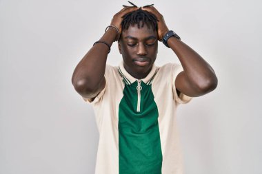 Afrika 'lı bir adam izole edilmiş arka planda duruyor. Ağrı ve migren yüzünden baş ağrısı ve stresten acı çekiyor. Eller başının üstünde.. 