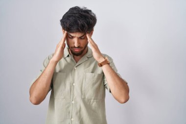 Beyaz arka plan üzerinde duran sakallı bir Arap adam, eli başının üstünde, stres yüzünden başı ağrıyor. migren ağrısı. 