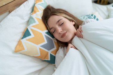 Beyaz bir kadın yatakta uzanıyor, yatak odasında uyuyor.
