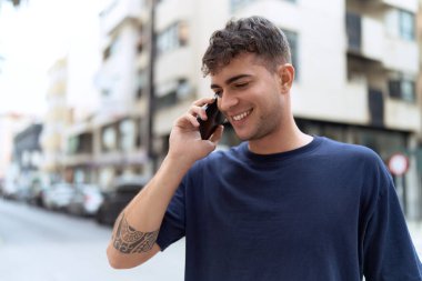 Genç İspanyol adam gülümsüyor. Kendine güveniyor. Sokakta akıllı telefondan konuşuyor.