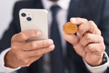 Young bald man using smartphone holding bitcoin at office