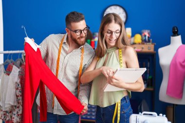 Man and woman tailors holding t shirt looking clothing design at clothing factory