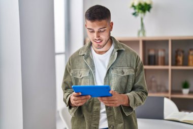 Genç İspanyol adam evde dokunmatik ped kullanıyor.